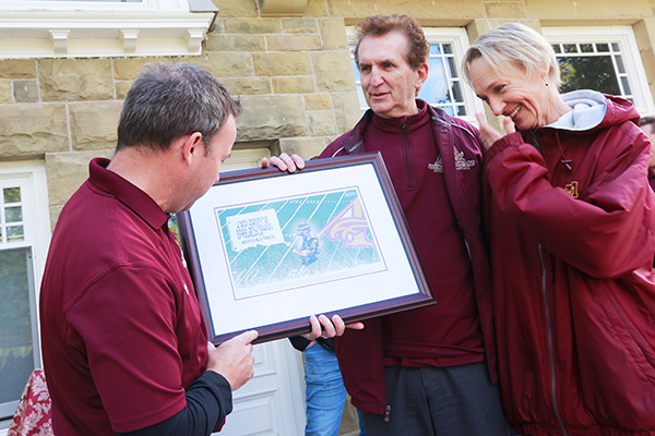 Athletics director Pierre Arsenault, left, presents Campbell and Verduyn with a thank you gift during the opening weekend of Alumni Field.